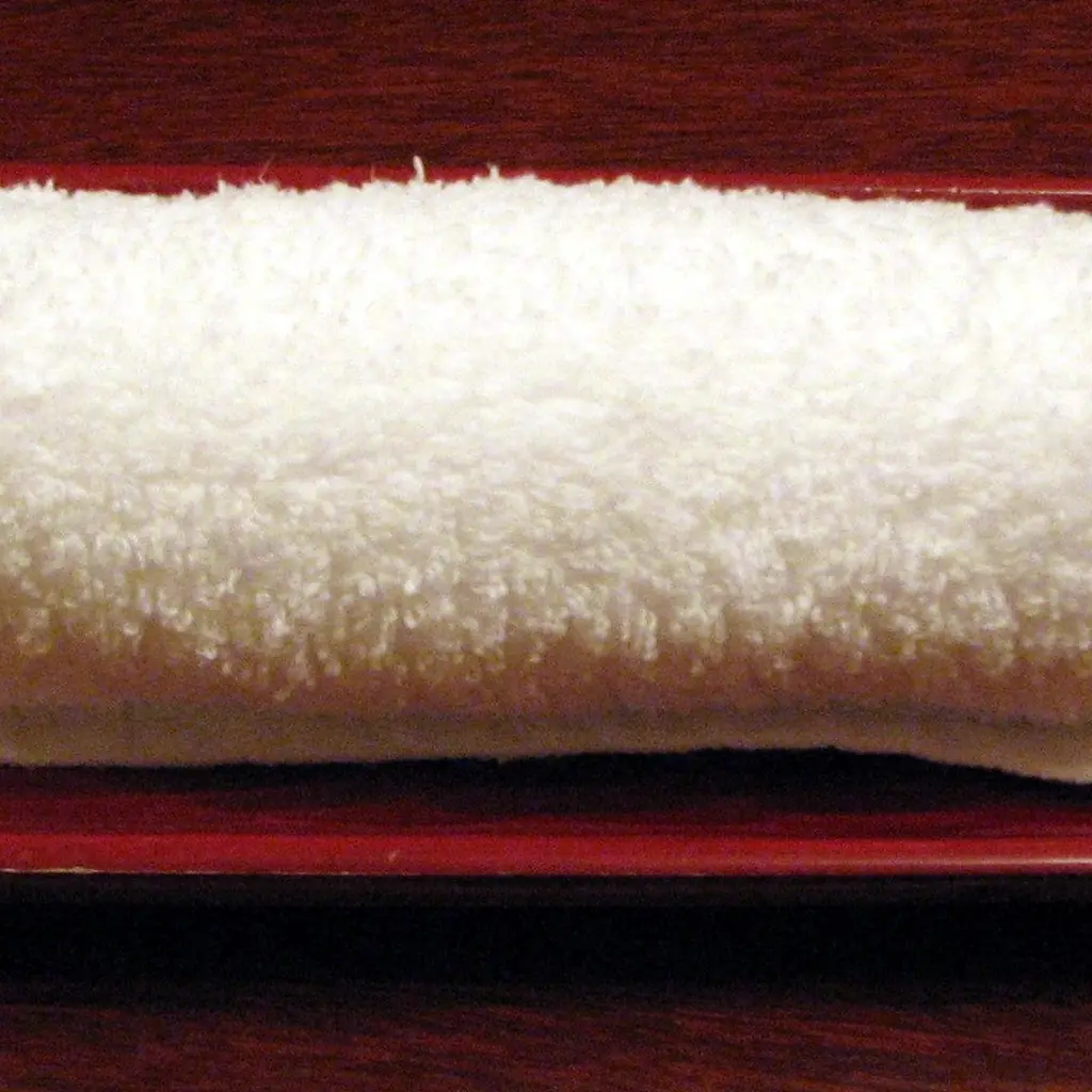 A rolled white hand towel on a tray.